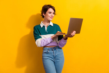 Photo of pretty nice young girl use laptop chatting typing wear shirt isolated on yellow color background
