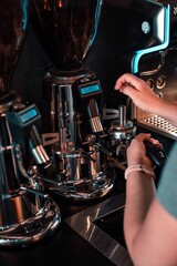 Young adult preparing a cup of coffee using a coffee maker on their countertop
