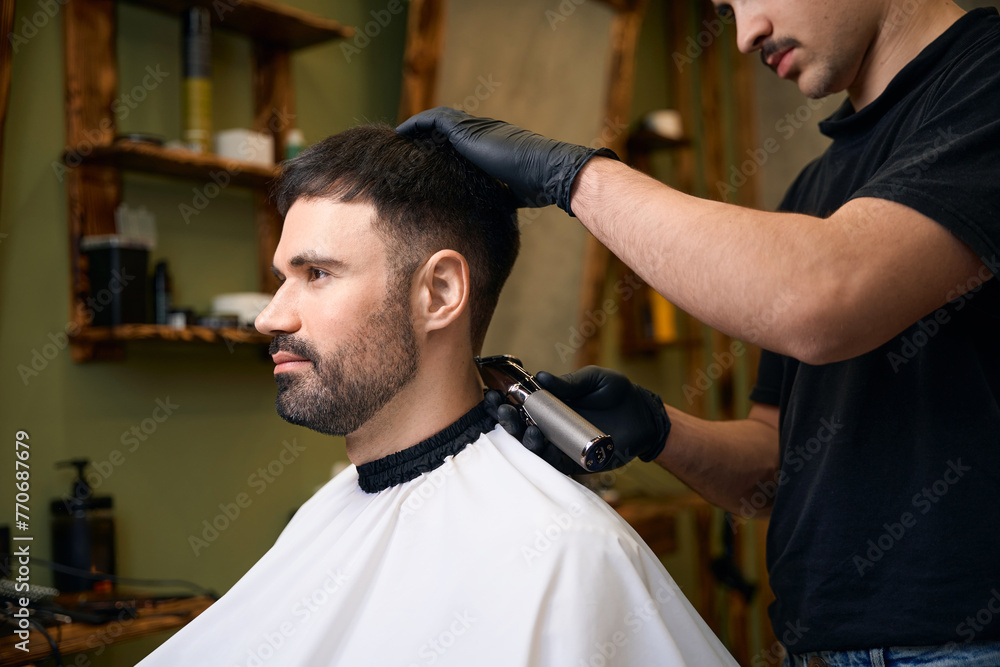 Wall mural Man hairdresser doing haircut for customer