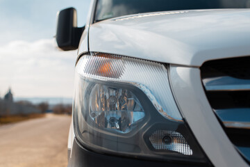 Close-up of headlight of white car outdoors.