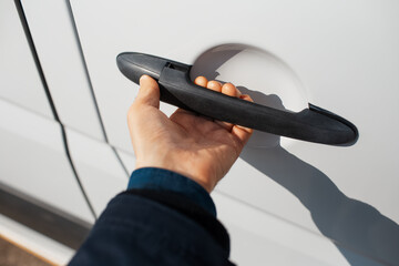 Close-up of hand opens handle of car door.
