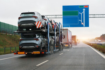 Naklejka premium Car carrier trailer truck with brand new off-road vehicles for sale. New car delivery. Car transporter trailer loaded with many new cars for the customers. Two-level modular hydraulic semi-trailer 