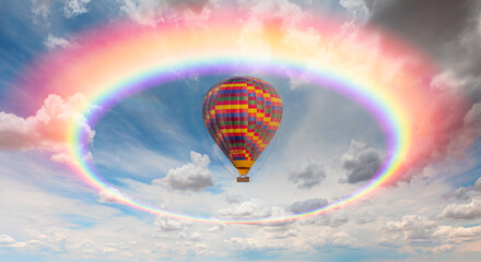 Colorful hot air balloon flying under storm clouds with rounded rainbow