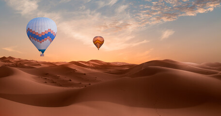 Hot air balloon flying over beautiful sand dunes in the Sahara desert with amazing cloudy sky - Sahara, Morocco
