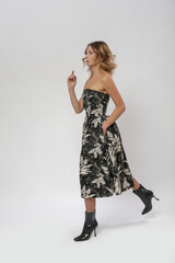 Serie of studio photos of female model in strapless tube top A line midi dress with flared skirt in tropical black floral pattern