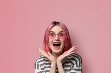 Excited surprised shocked astonished very happy pink hair woman wear braces brackets sunglasses eye...