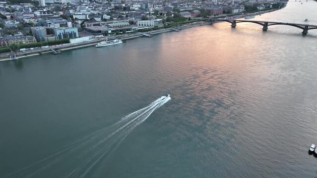 High drone footage of speed boat sailing on Rhine River heading to Theodor Heuss Bridge, Germany