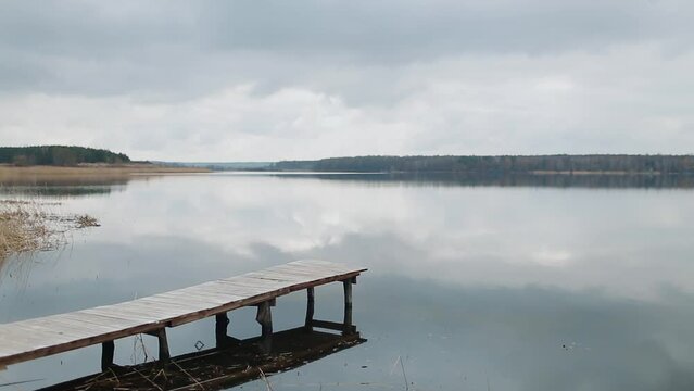 Walking wooden pier for swimming. Spectacular gray and dramatic spring clouds over a calm river. Environmental protection.