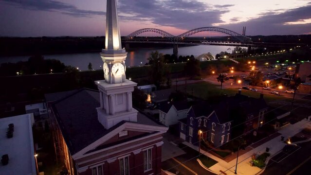 Drone shot of Town Clock Church with Sherman Minton Bridge in the background at sunset, USA