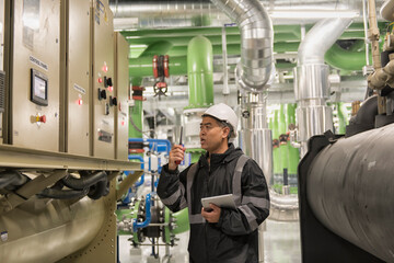 worker operating a machine.  Service Engineer checking and Recode data on Chiller Plant.