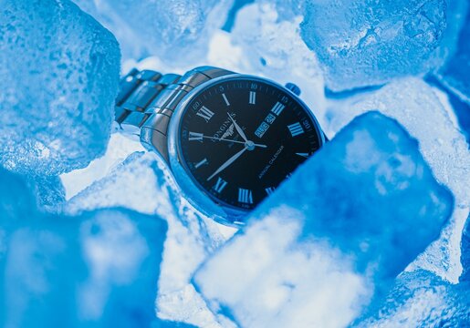 a silver and black watch sitting on top of ice chunks