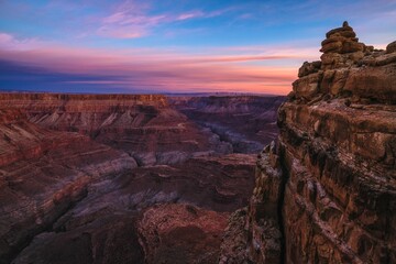 a large cliff overlooks the vast, rugged canyon below