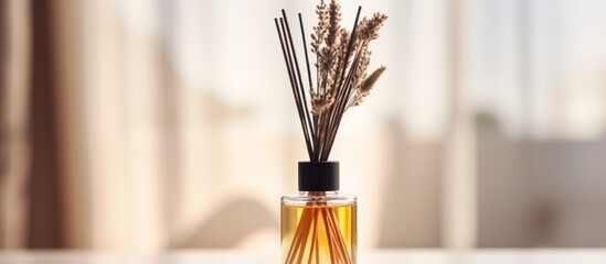 A glass bottle of scented oil with sticks is displayed on a table as a reed diffuser, containing a...