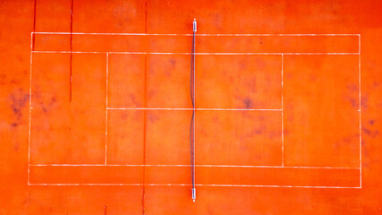 An aerial perspective showcases the geometric beauty of a vibrant orange tennis court, the bold...