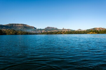 Scenic view of Arthur Lake in Bhandardara, India is seen, with lush green hills and trees