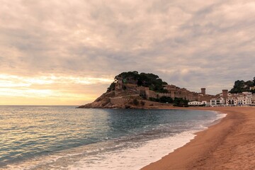 Old castle on a rocky hill on the tropical beach with white sands in Tossa De Mar - obrazy, fototapety, plakaty