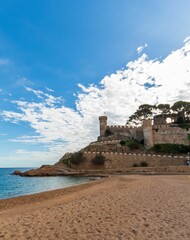 Fototapeta na wymiar Old castle on a rocky hill on the tropical beach with white sands in Tossa De Mar