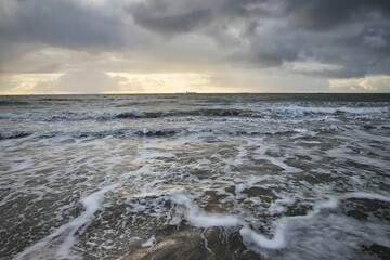 Beach scene featuring a serene sunset with waves rolling in on the sandy shore, Isle of Wight