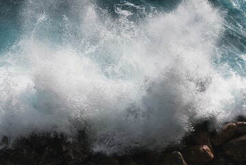 Large wave in the ocean crashing onto the shoreline, creating a white foam