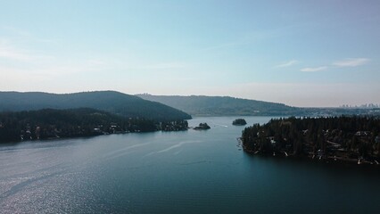 Island surrounded by the crystal blue waters of the ocean, with lush green hills in the far distance