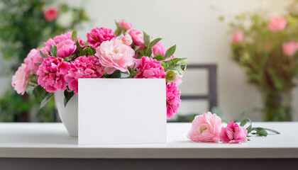 Mock up of white blank paper card and beautiful pink flowers. Spring bouquet on table.
