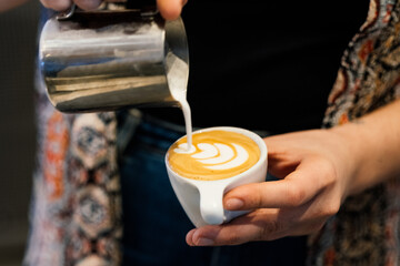 a barista holding a cup of coffee and making latte art
