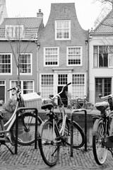 Fototapeta na wymiar Picturesque Netherlands in black and white. Bicycles parked alongside a channel on beautiful old buildings background.