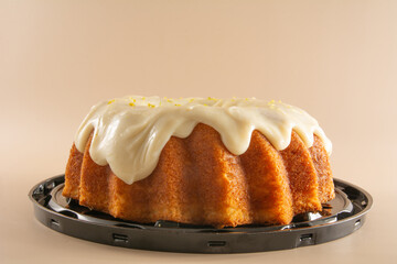Classic lemon cake with creamy milky glaze with lemon zest beige background