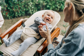 Joyful laughing baby holds finger of mother's hand.