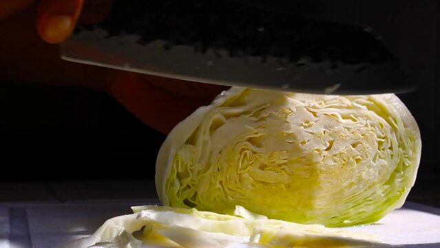 Hand cutting and threading raw cabbage vegetable with chef knife 