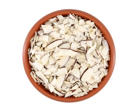 Desiccated coconut chips in an earthenware bowl. Top view. White background.