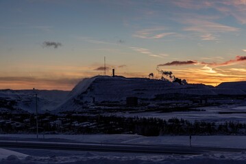 Majestic winter scene of a snow-covered landscape illuminated by a spectacular sunset sky.