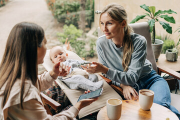 Two women talking in a cafe. Mother with baby.