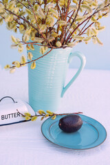 Avocado, butter dish and a bouquet of willows together on the table. Spring mood, bright look.