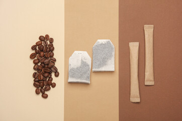 Coffee beans, tea bags and disposable sticks with sugar on a beige background