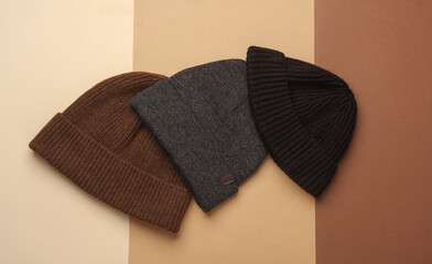 Woolen warm winter hats on beige brown background