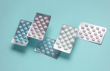 Many blisters of tablets floating on a blue background. Medicine concept