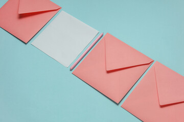 Pink envelopes and white blank card with a pen on a blue background