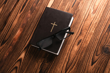 Bible book with eyeglasses on wooden table