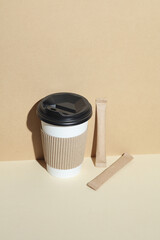 Cardboard cup for hot drinks, sugar or coffee in pack on beige background with shadow