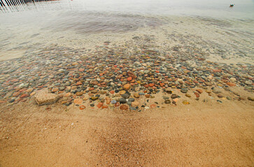 colorful beach stones in the water on the shore