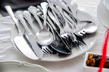 silver cutlery set of knives, forks and spoons for Christmas with plate decoration and white tablecloth