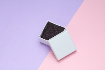 White box with black tea on pastel background