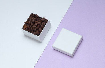 Coffee beans in white cardboard box on pastel background