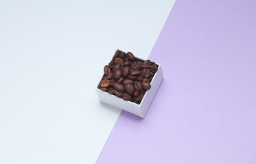 Coffee beans in white cardboard box on pastel background