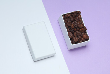 Coffee beans in white cardboard box on pastel background