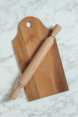 Kitchen board with rolling pin on marble background