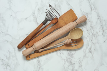 Wooden kitchen utensils on a marble background. Top view - obrazy, fototapety, plakaty