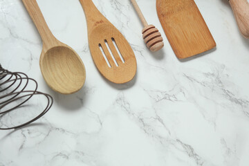 Wooden kitchen utensils on a marble background. Top view. Copy space