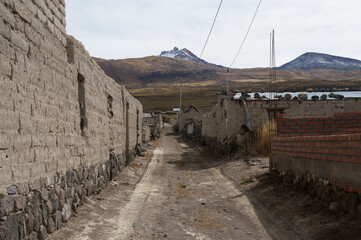 Street in a remote village called Jirira in Bolivia with adobe buildings, in the background you can see mountains and the extinct Tunupa volcano